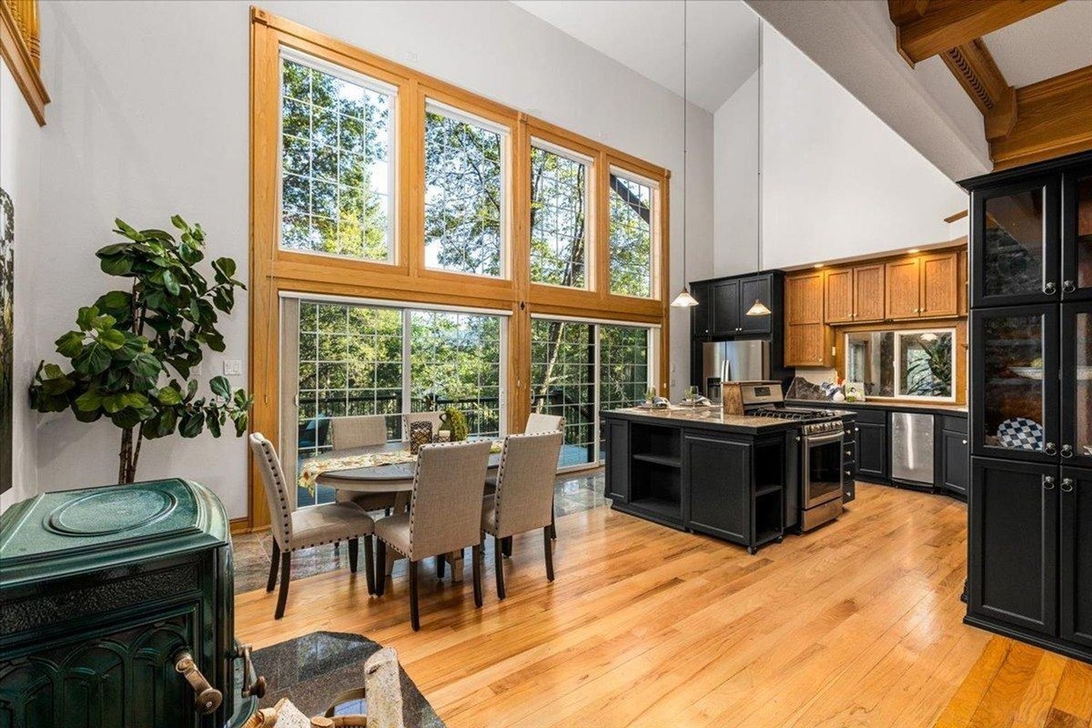 Kitchen and dining space offer double-height windows that fill the room with natural light and showcase forest views.