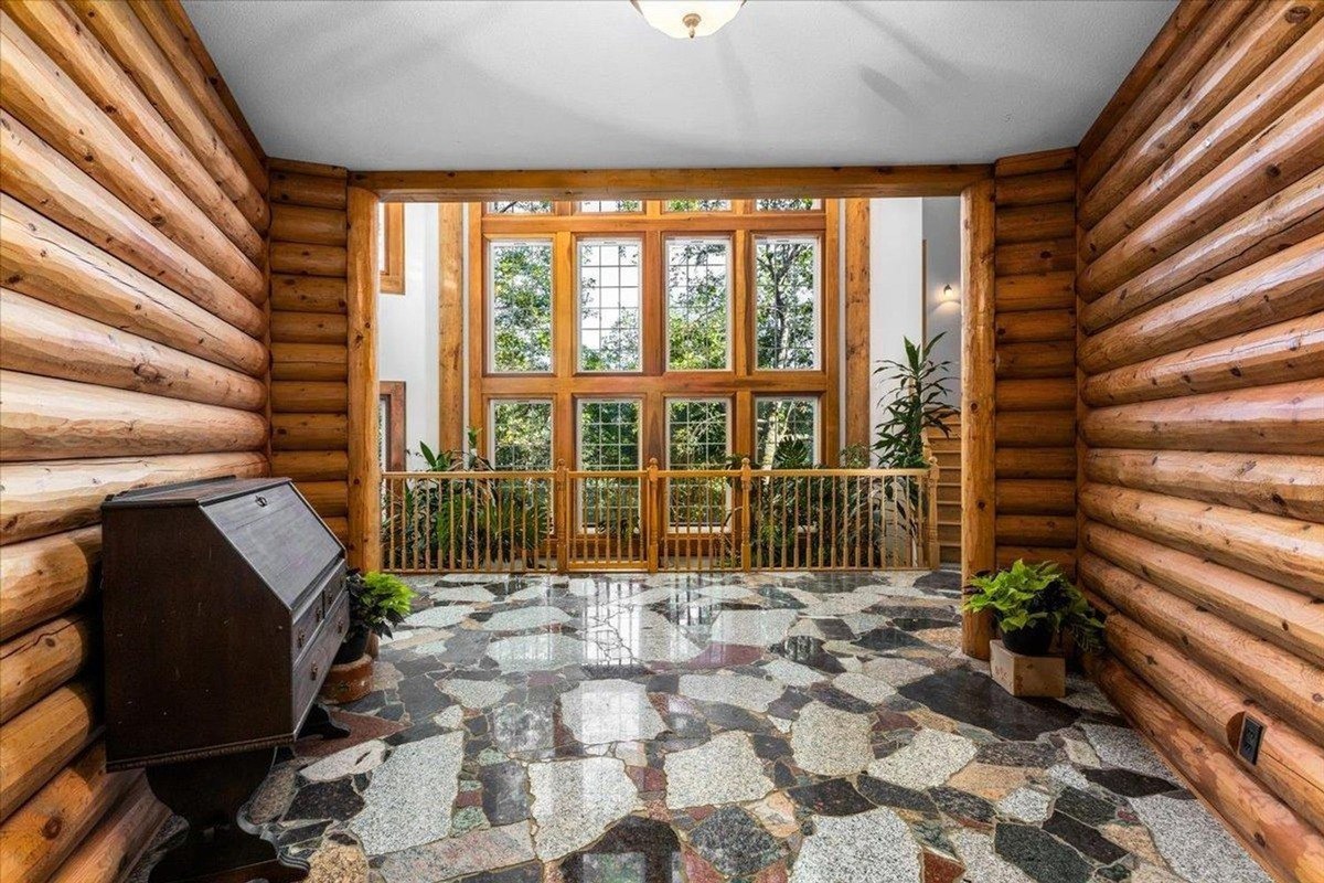 Spacious entryway features log-paneled walls, large windows, and natural stone flooring.