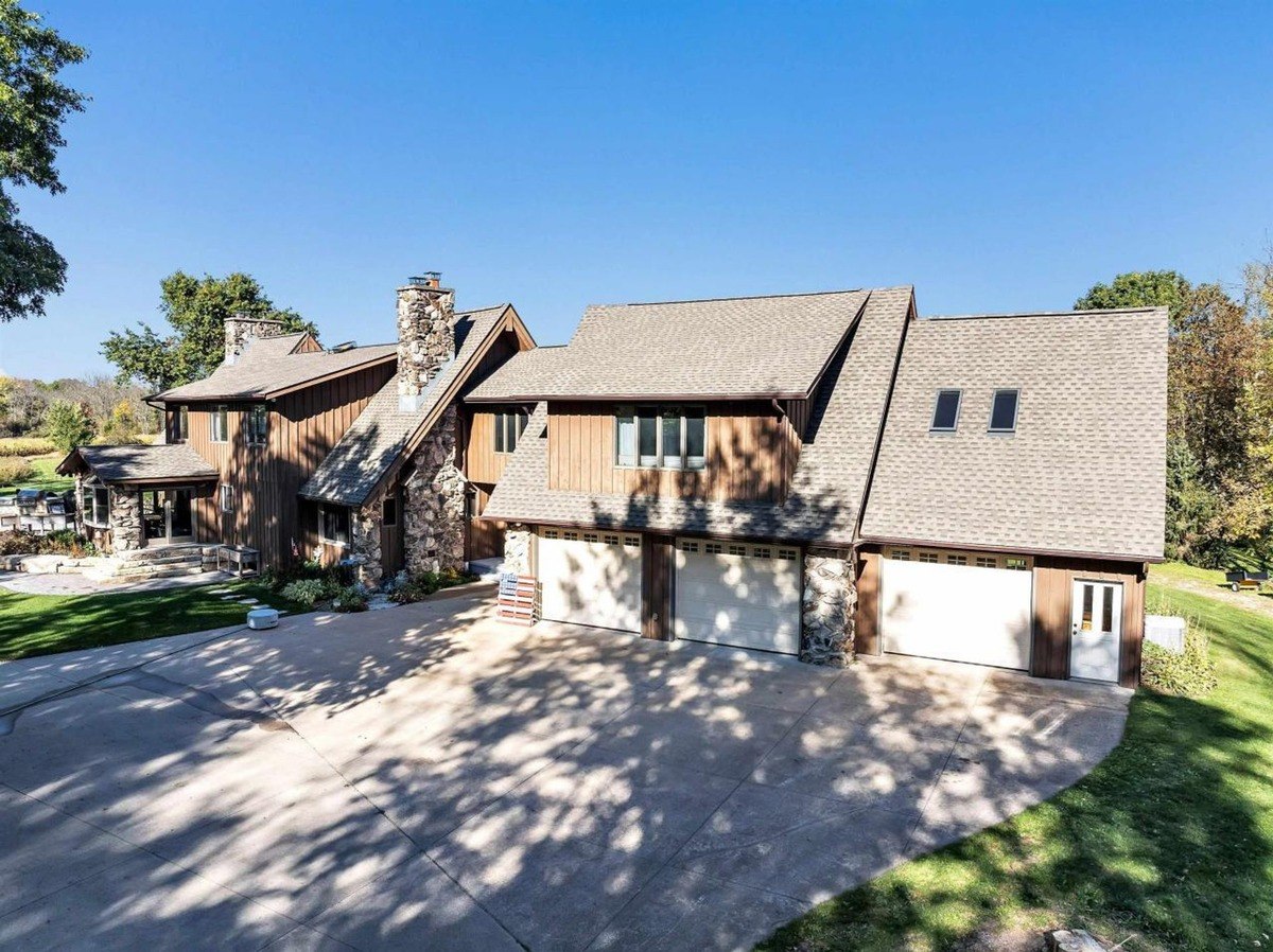 Stone accents highlight the wood siding of this house, which also includes a spacious three-car garage.