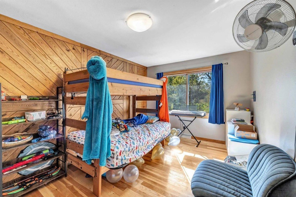 Child's bedroom has wood walls, bunk bed, keyboard, and ceiling fan.