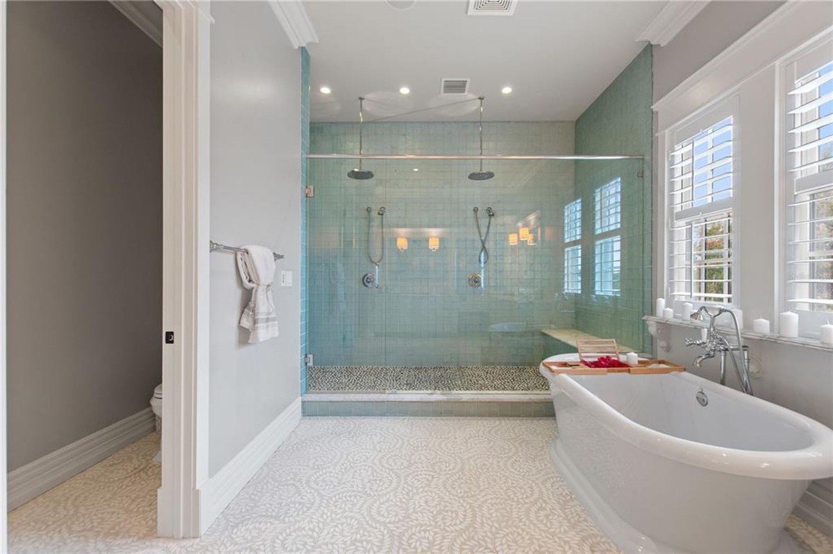 Bathroom features a large soaking tub, a walk-in shower with glass enclosure, and patterned floor tiles.