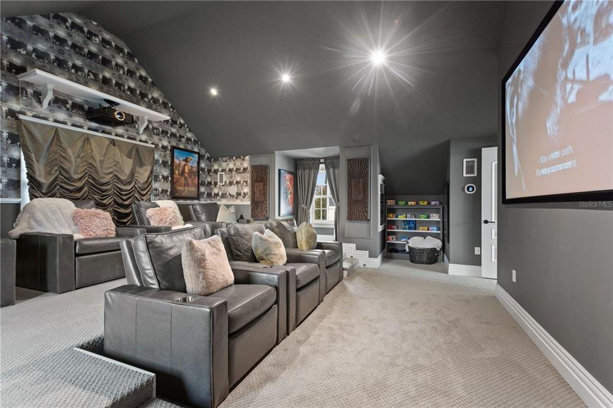 Home theater features gray leather reclining seats, a large projection screen, and gray walls with western-themed decor.