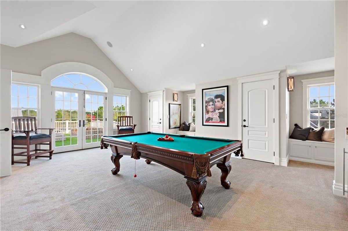 Game room features a pool table, carpeted floor, and large windows offering a view of a patio.