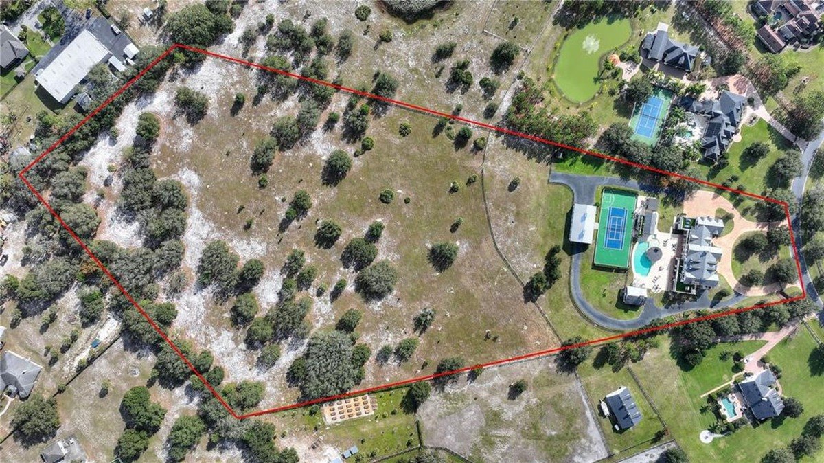 Aerial view shows large property with a house, pool, tennis court, and barn, outlined in red.