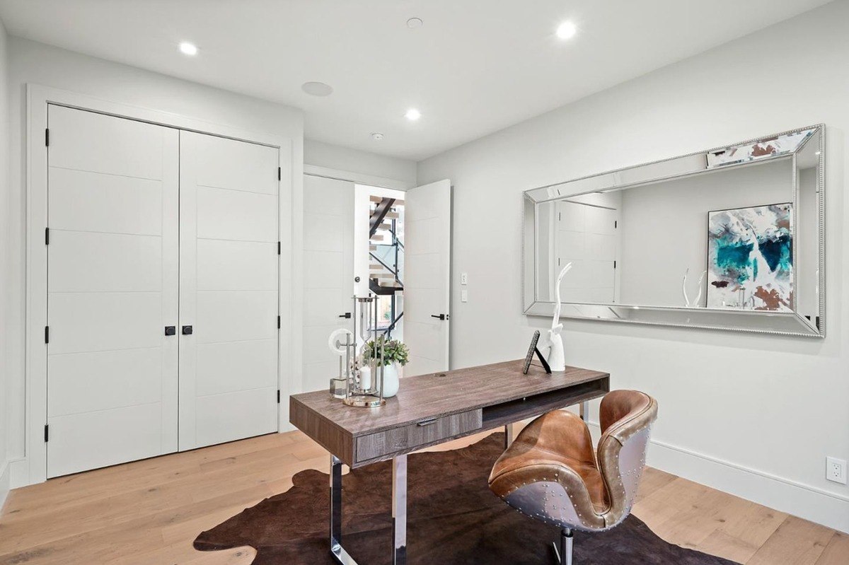 Home office with contemporary decor a home office featuring a wood desk, leather chair, and a large decorative mirror.