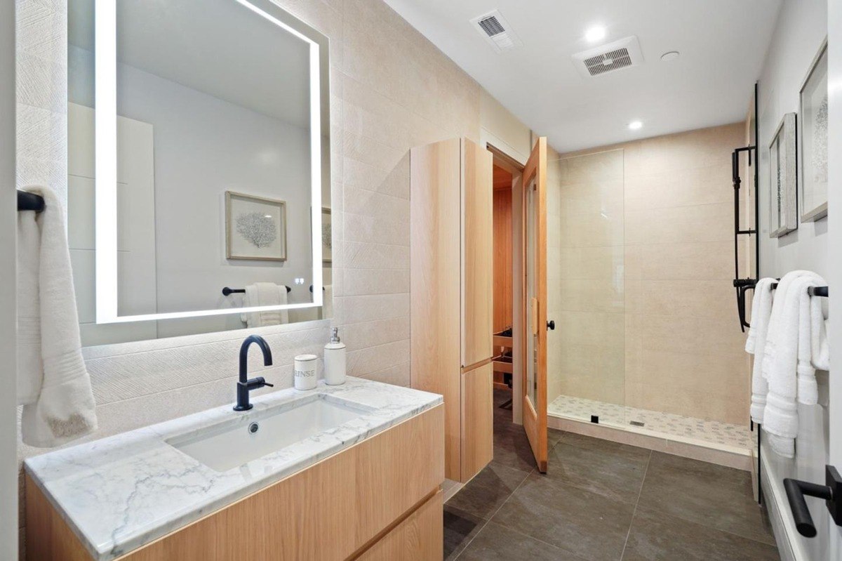 Spa-like bathroom a bathroom featuring a large mirror, wood cabinets, and a steam shower.