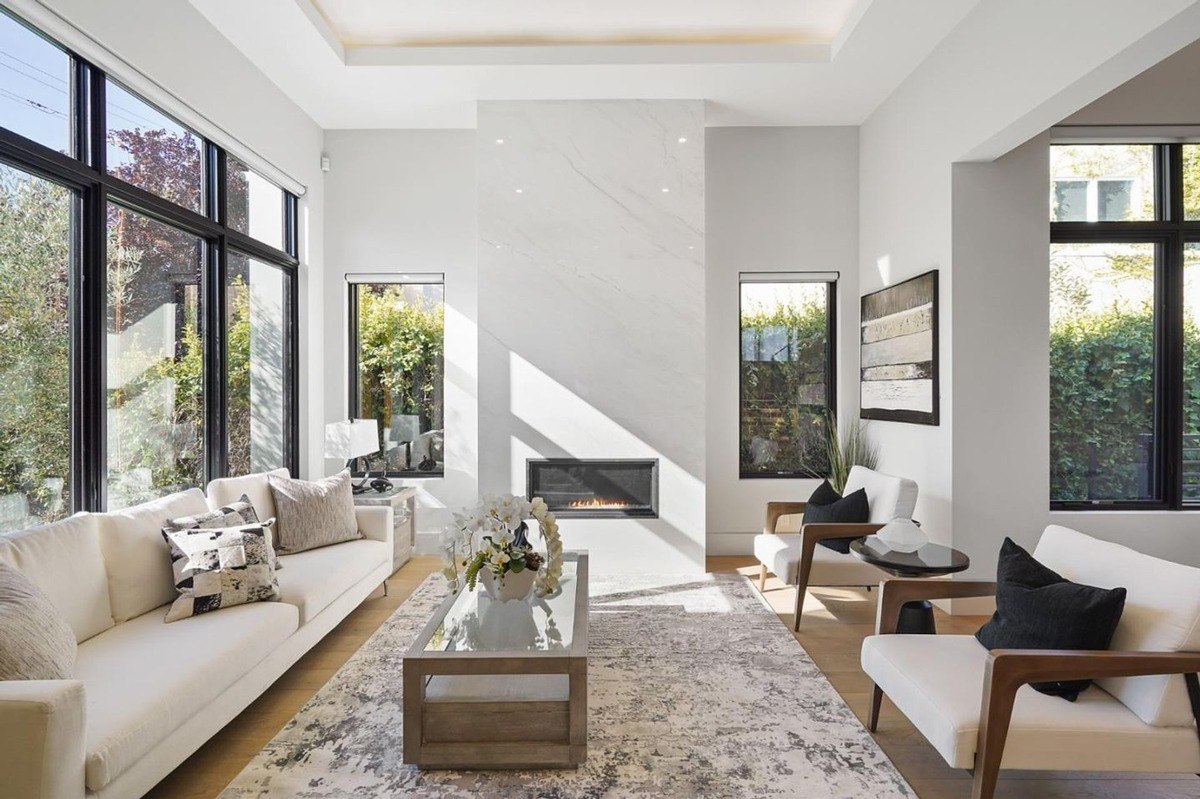 Bright living room a living room with high ceilings, large windows, and a marble accent fireplace.