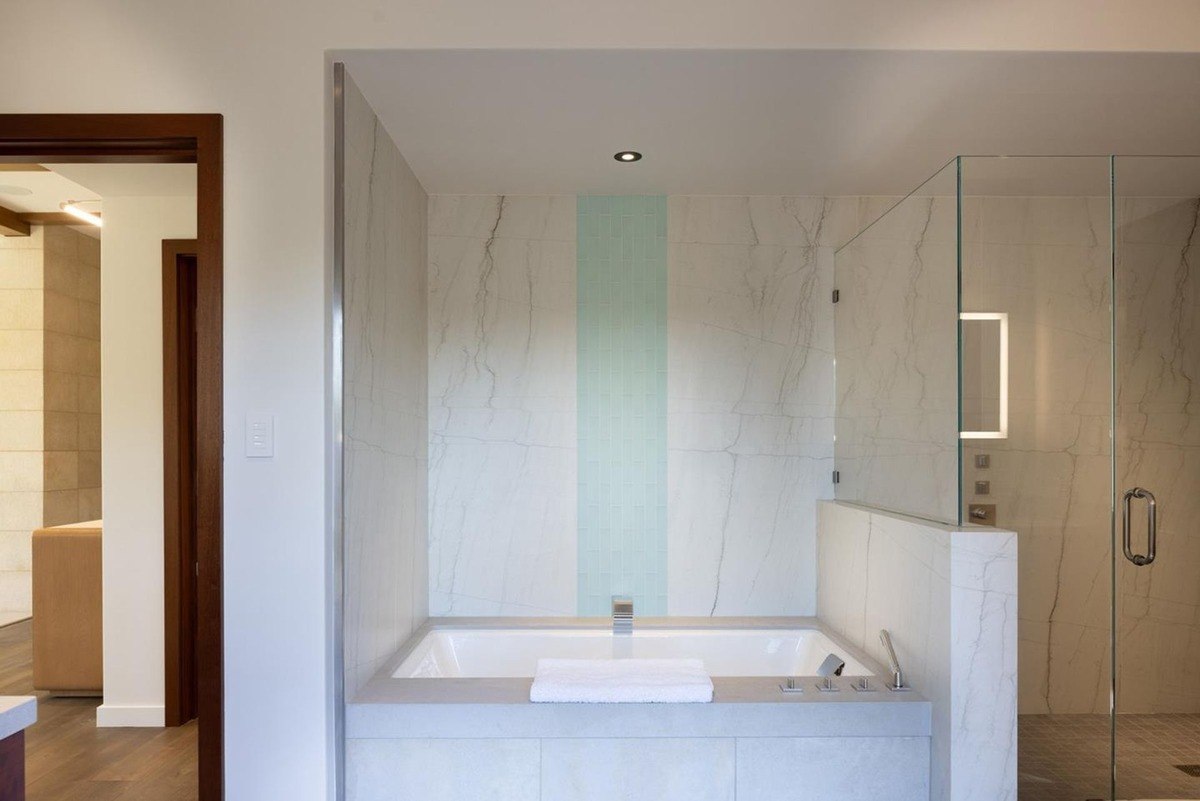 Luxurious bathroom with a freestanding bathtub, a walk-in shower, and marble tile walls.