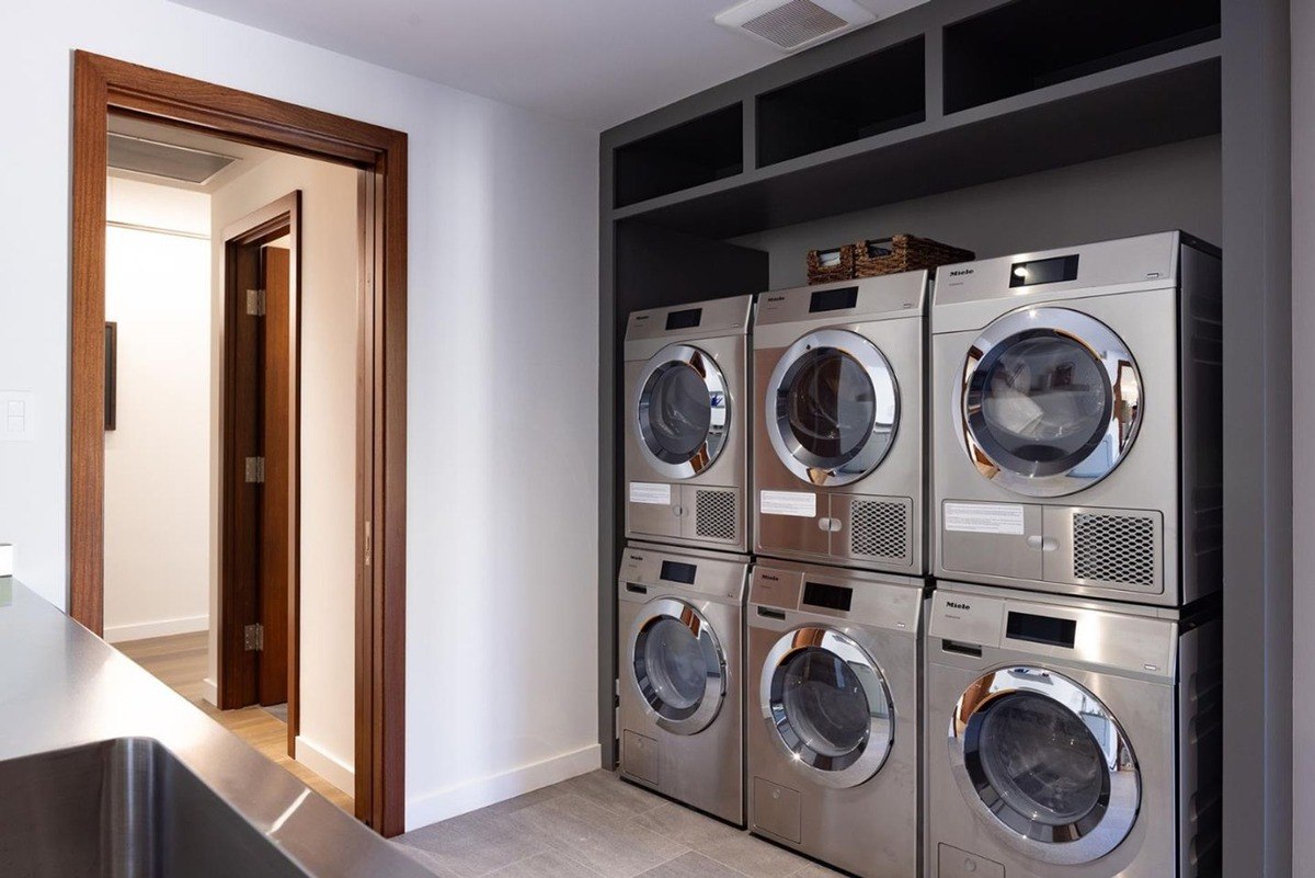 Laundry room with multiple high-end washing machines and dryers, offering convenience and efficiency.