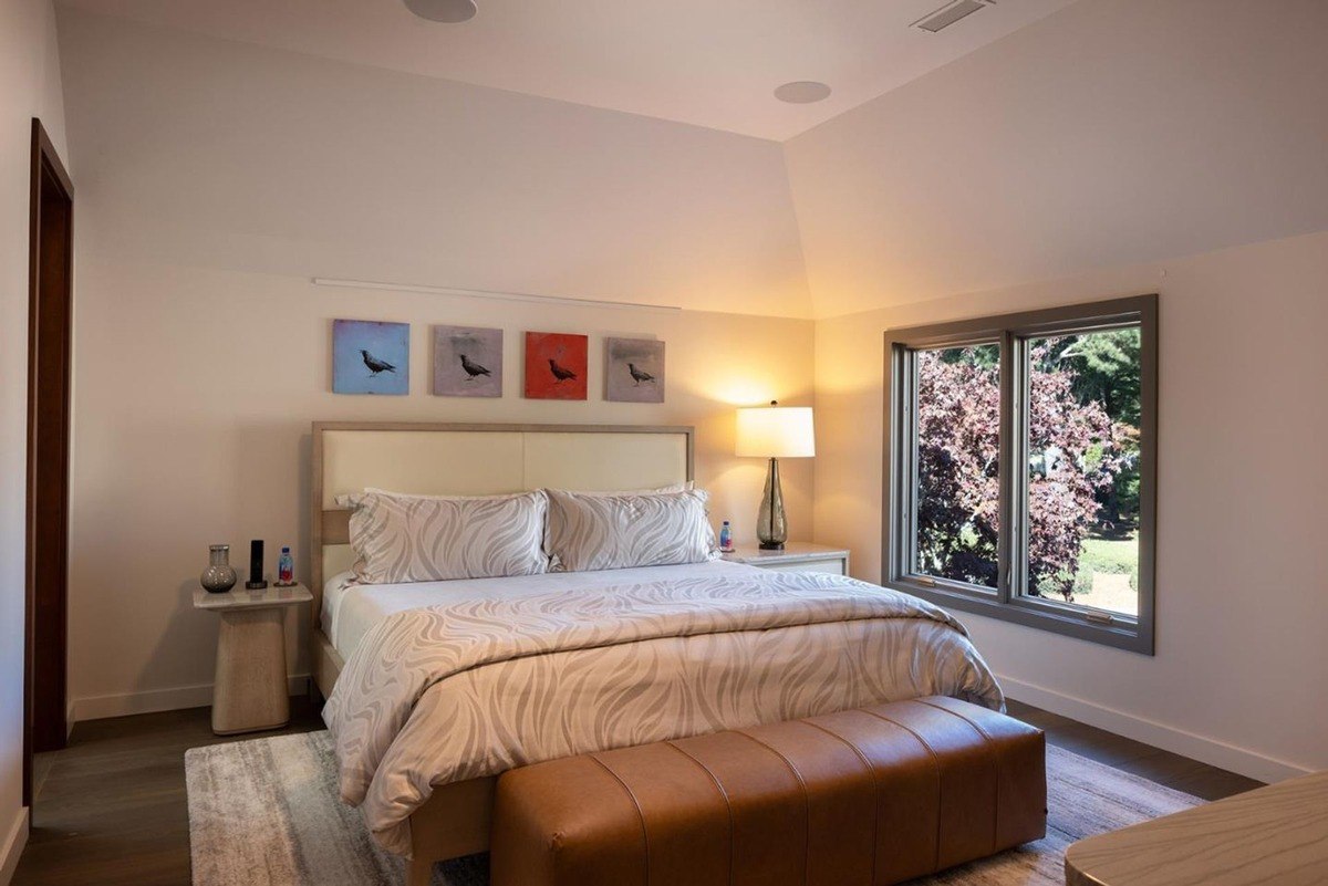 Cozy bedroom with a king-sized bed, a bench at the foot, and a balcony offering breathtaking ocean views.