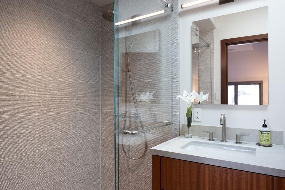 Modern bathroom with a walk-in shower, a vanity with a countertop sink, and a mirror.