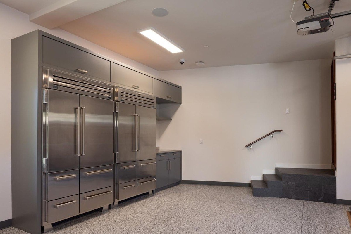 Garage with a set of built-in stainless steel refrigerators, a staircase leading to an upper level, and a projector hanging from the ceiling.