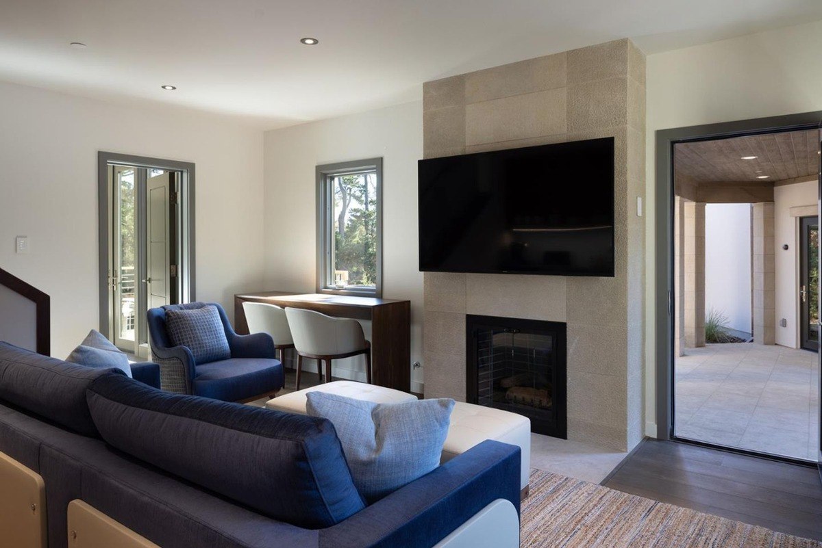 Living room with a fireplace, a flat-screen TV, and comfortable seating, offering access to an outdoor patio.