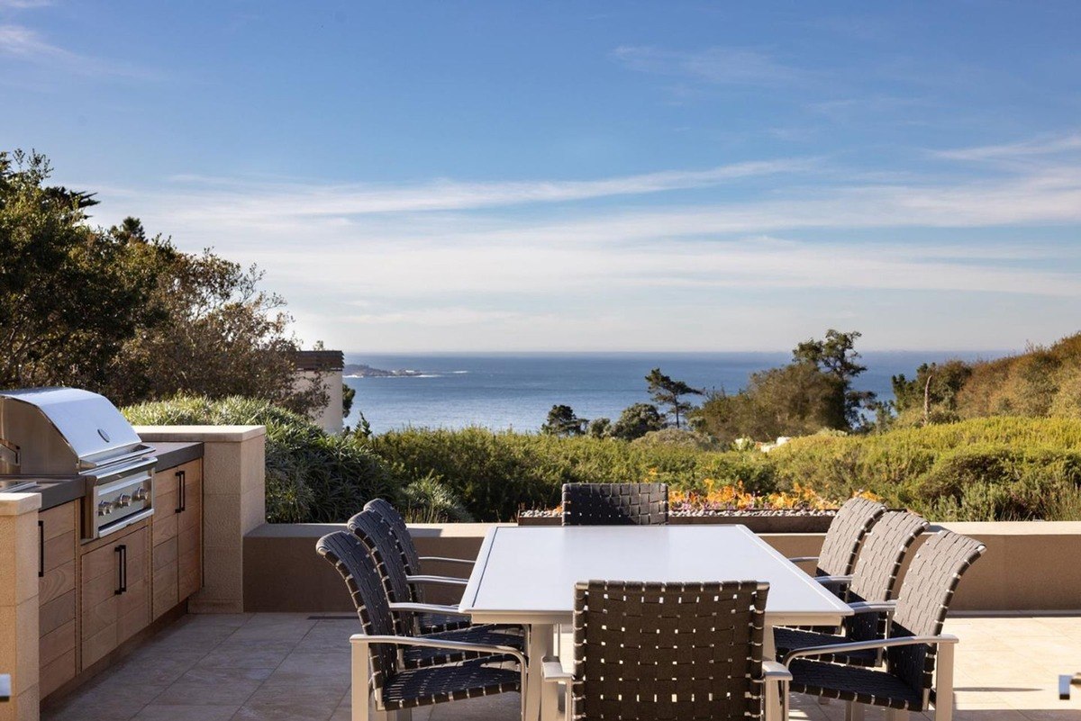 Outdoor dining area with a large table and chairs, a built-in barbecue grill, and breathtaking ocean views.