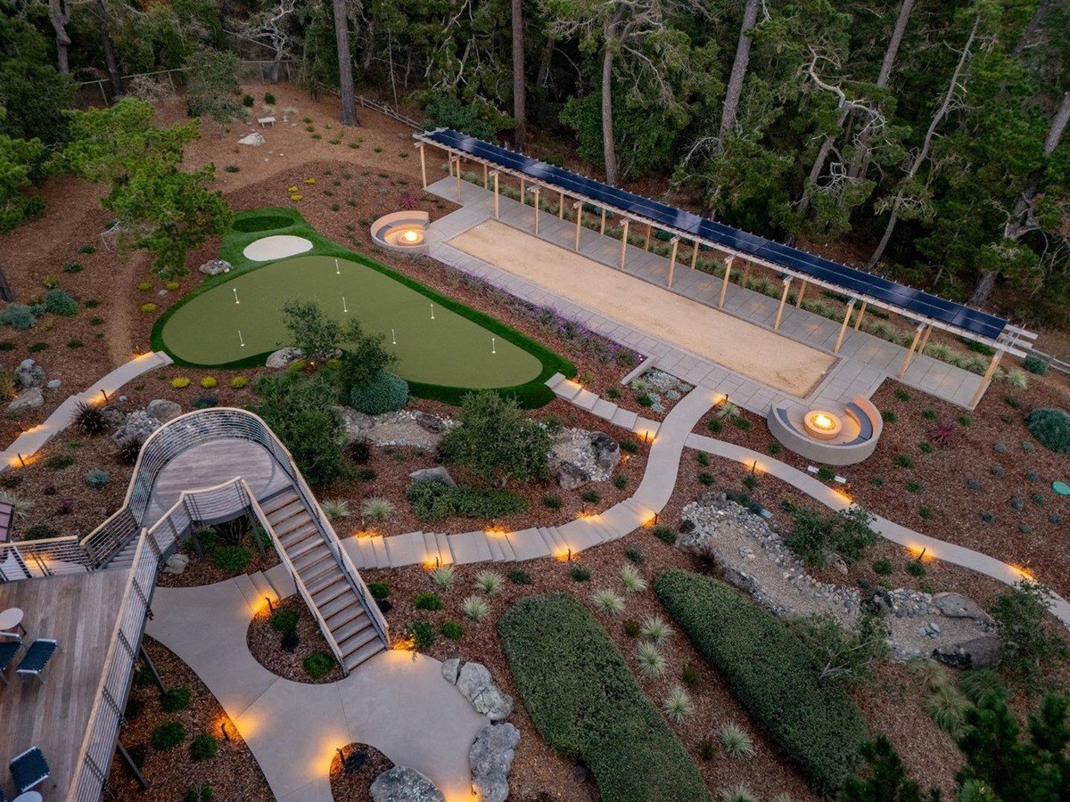 Beautifully landscaped outdoor space with a putting green, a bocce ball court, fire pits, and winding pathways, creating a perfect space for entertainment and relaxation.