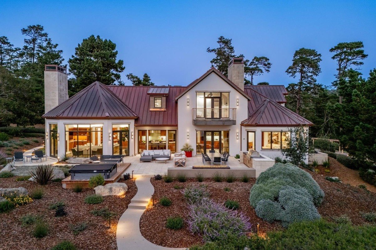 Modern farmhouse-style home with a copper roof, a spacious patio, and a beautifully landscaped yard.