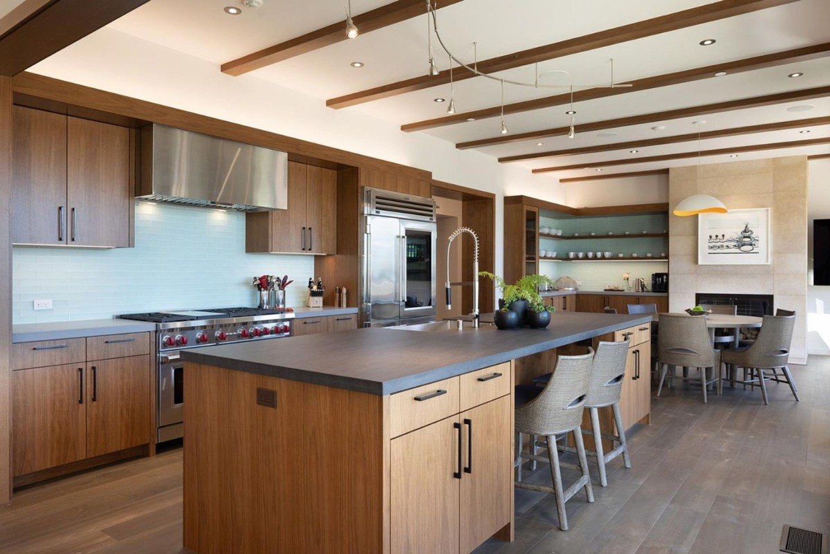 Kitchen with a large island, stainless steel appliances, and a warm color palette.