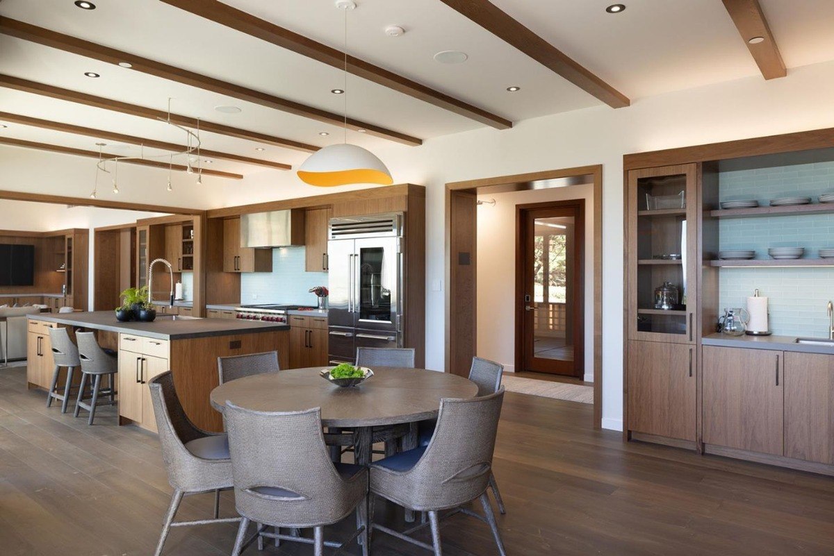 Spacious dining area with a round table and chairs, adjacent to the modern kitchen, showcasing a seamless flow between the spaces.