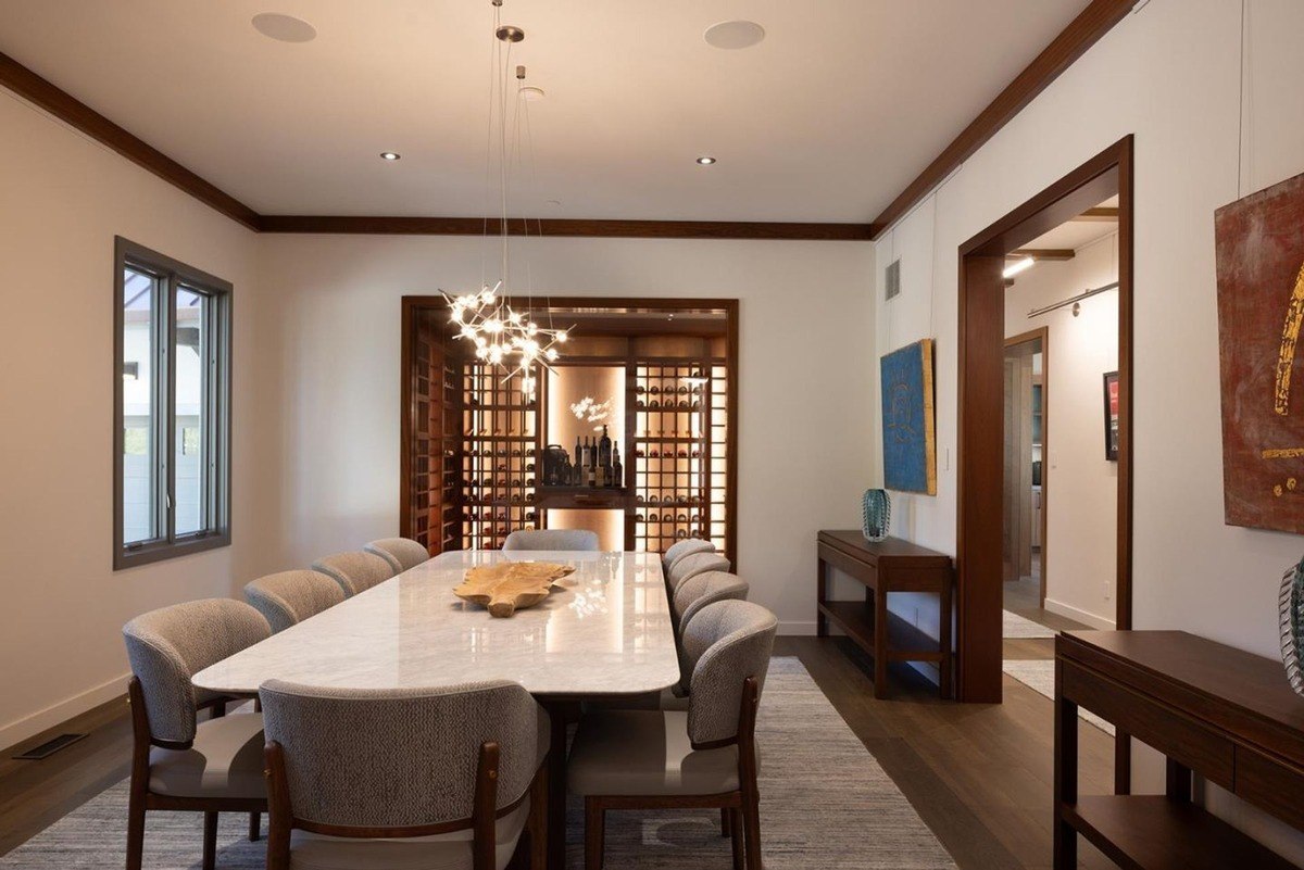 Formal dining room with a large marble table, comfortable seating, and a built-in wine display, creating an elegant and sophisticated ambiance.