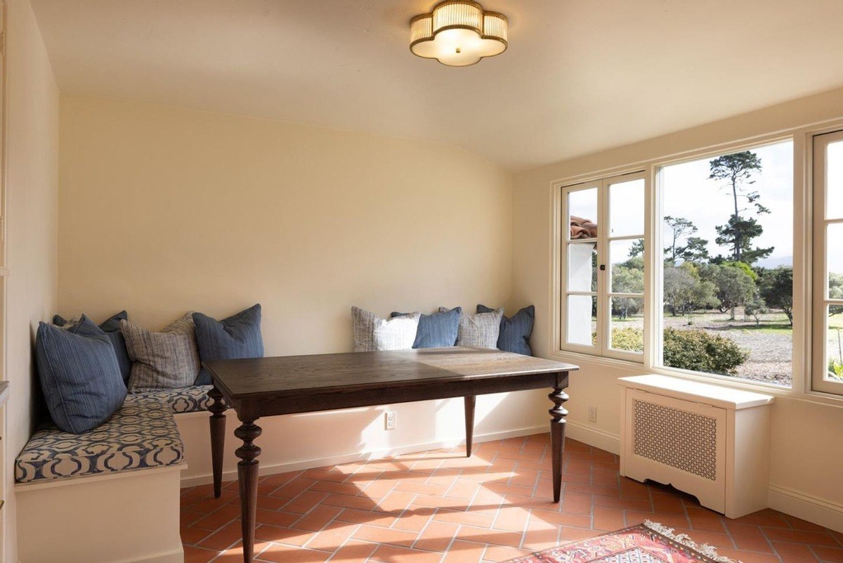 Cozy breakfast nook with a built-in bench seating, a wooden table, and a large window offering views of the surrounding landscape.