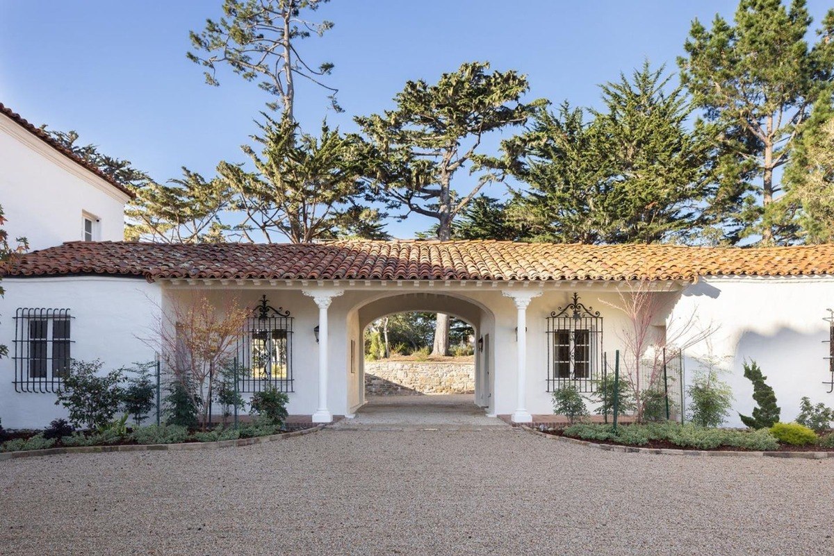 Carming white house with a red tile roof and a covered walkway leading to the entrance.