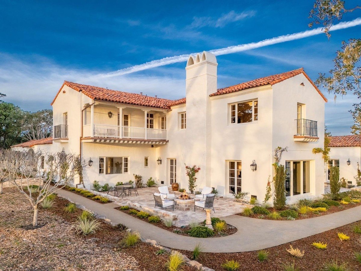 Big white house with a red tile roof and a nice patio with a fire pit in front.