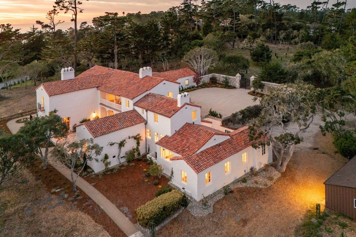 Big white house with a red tile roof at sunset. You can see the house from above.