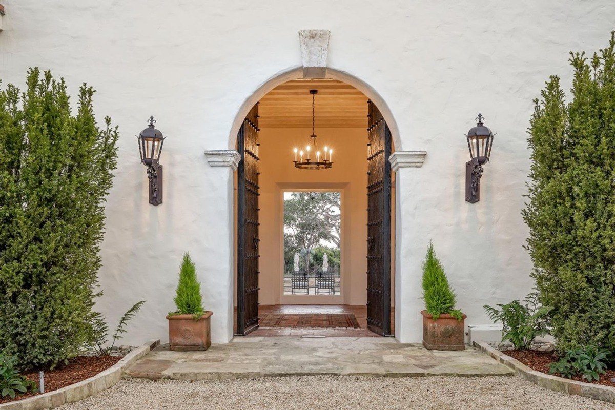 Inviting archway framed by lush greenery opens into a well-lit passageway, enhancing the sense of warmth.