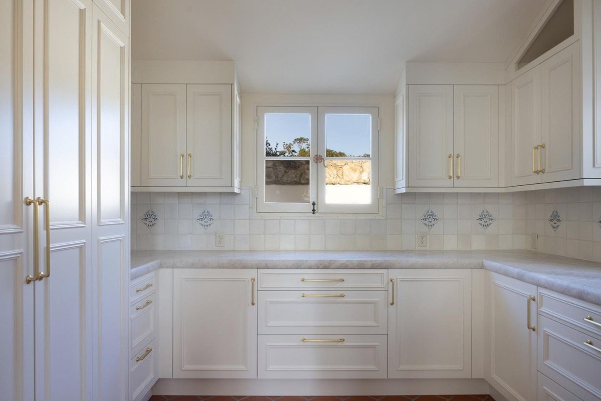 Stylish kitchen layout features elegant pendant lights above a dark wood island, creating a focal point.