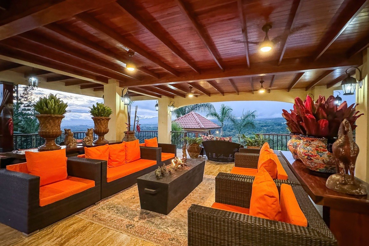 Outdoor lounge area has orange couches, fire pit, and mountain view.