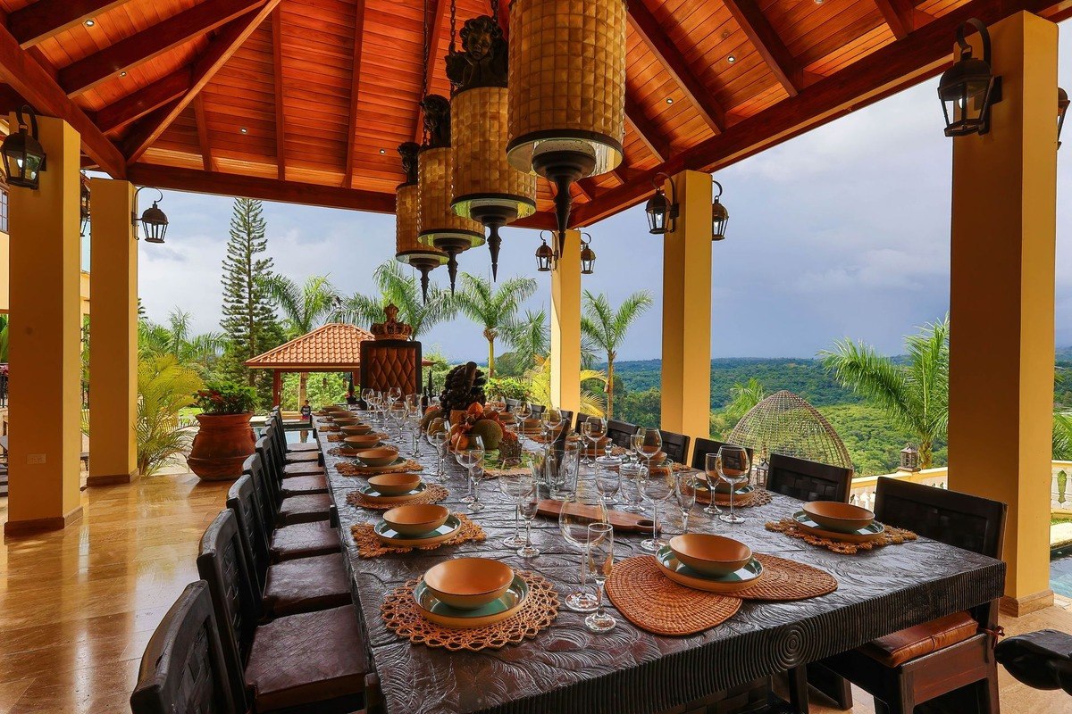 Long outdoor dining table has many place settings and mountain view.