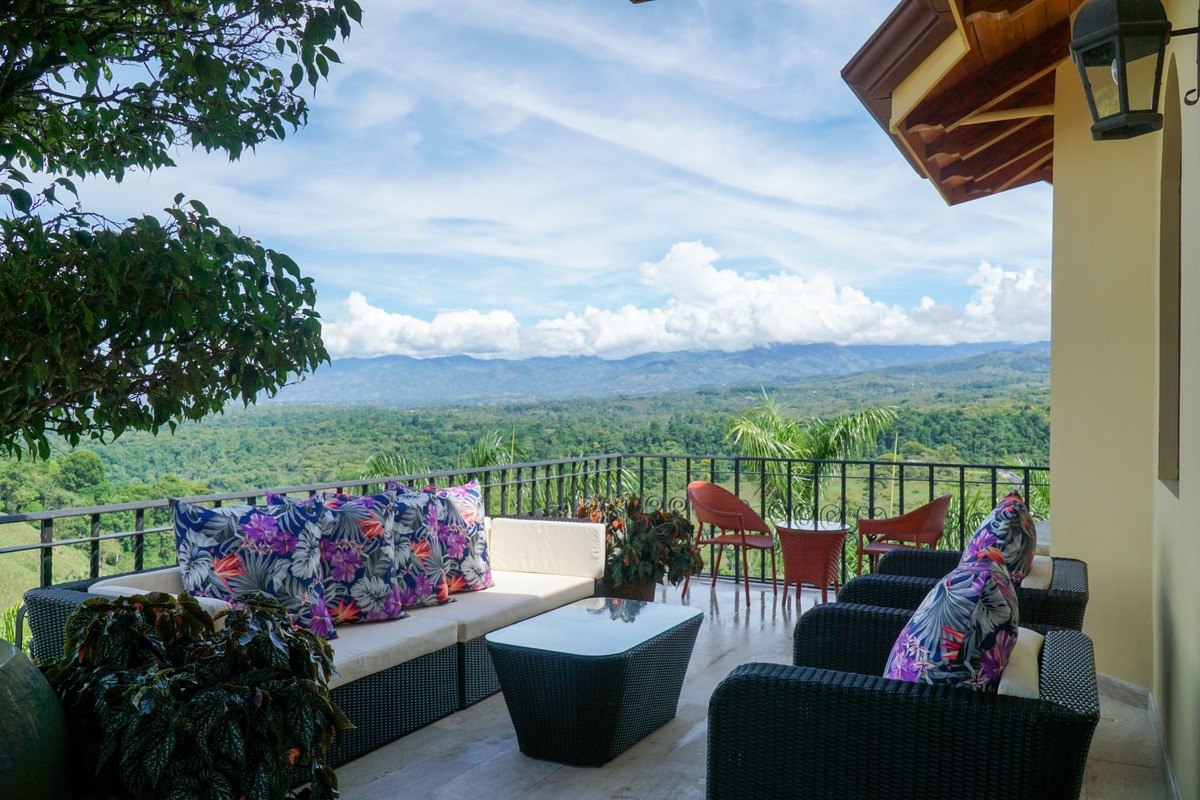 Outdoor seating area has mountain view and colorful pillows.