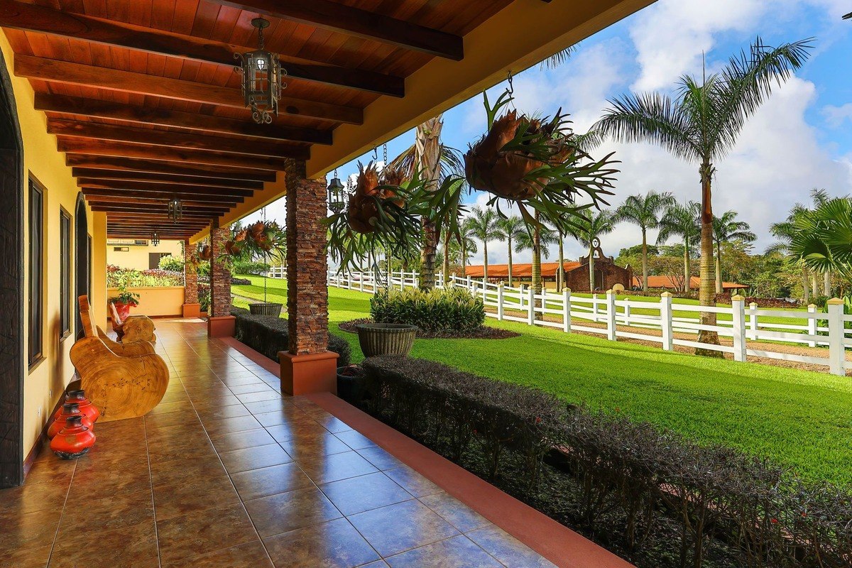 Covered patio has wood ceiling, tile floor, and view of green lawn.