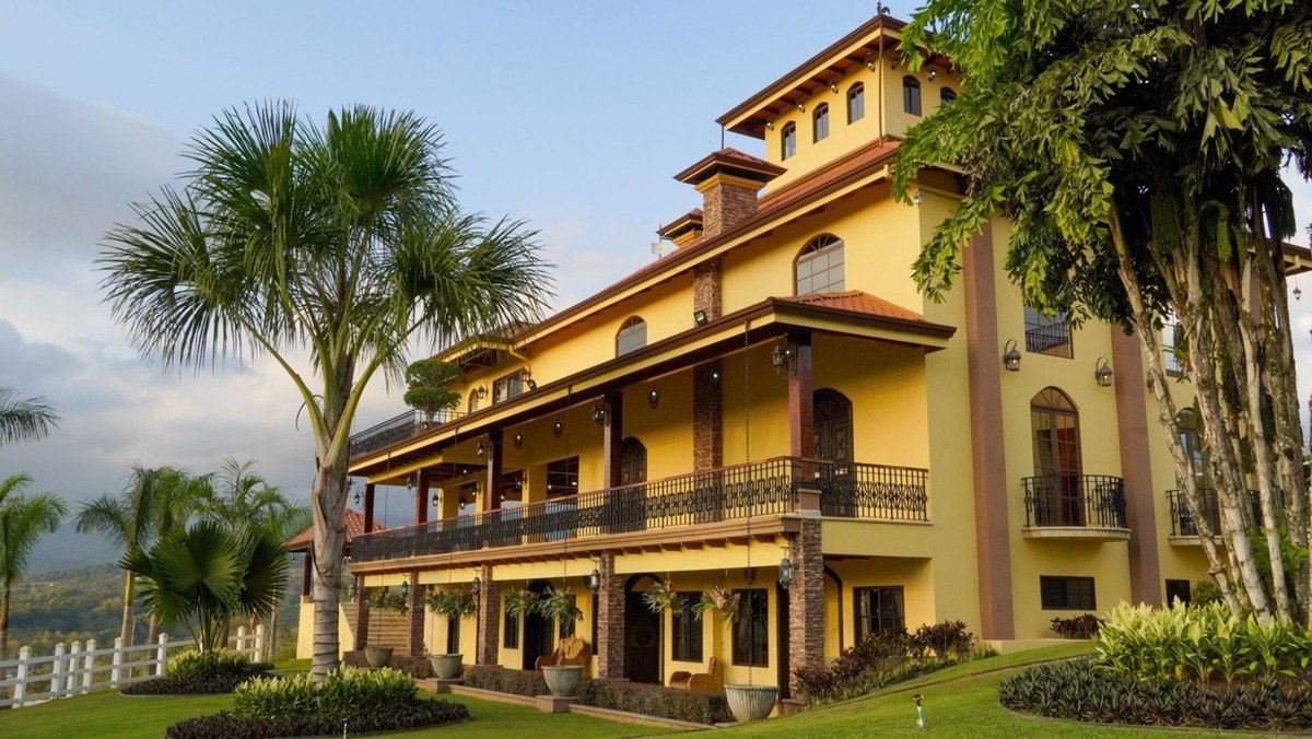  Yellow house has multiple levels, balconies, and lush landscaping.