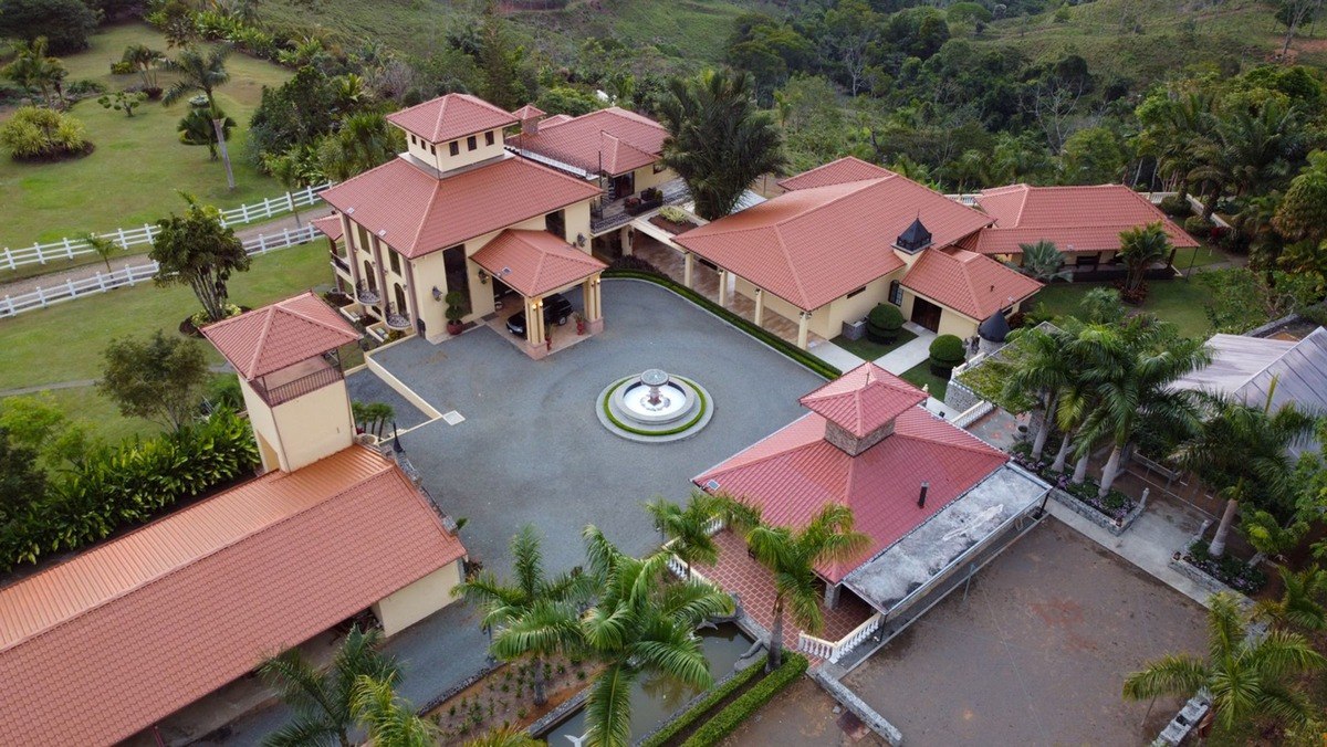 Aerial view shows large estate with multiple buildings and fountain.