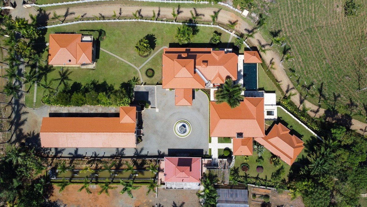 Aerial view shows large estate with multiple buildings and pool.