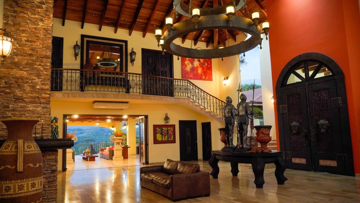 Grand entryway has large chandelier, staircase, and view.