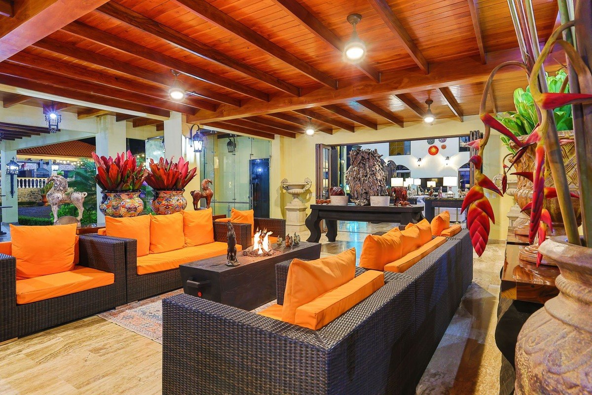 Lounge area has orange couches, fire pit, and wood ceiling.