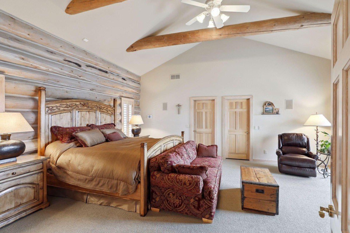 Master bedroom a spacious room with log walls, a beamed ceiling, and elegant furniture.