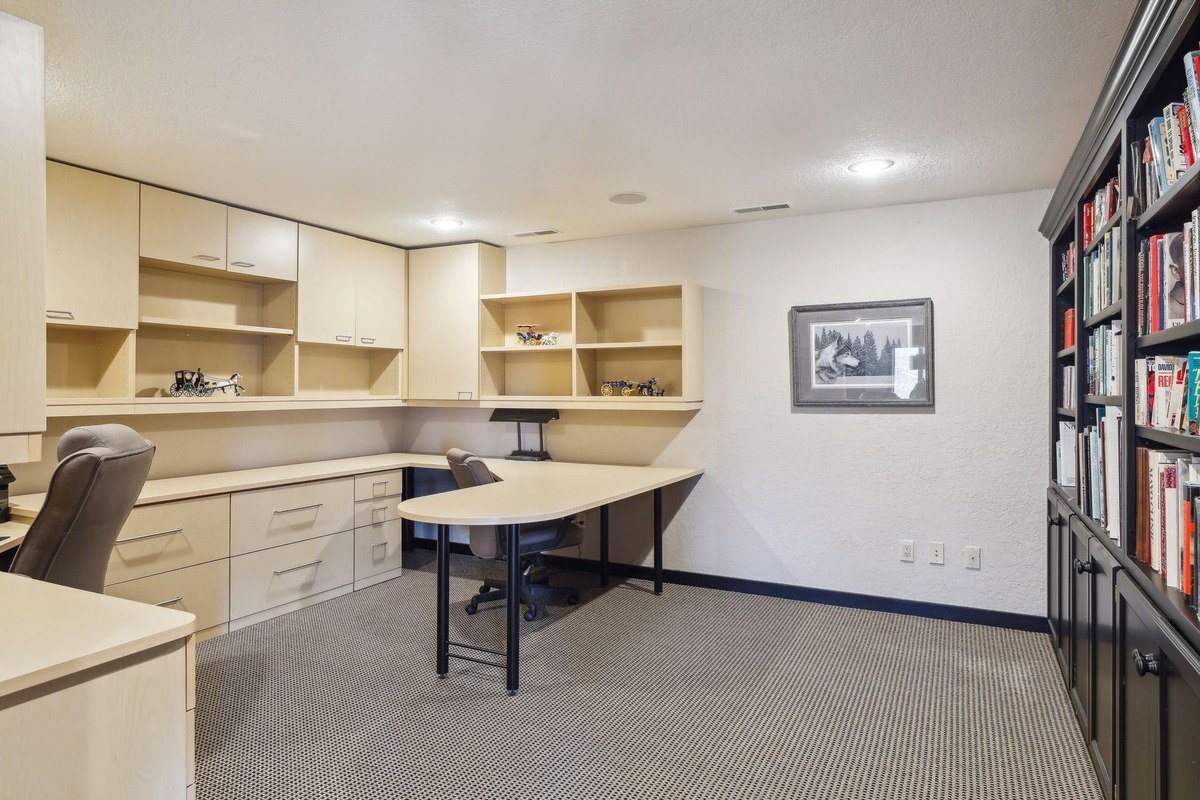 Office space a home office with built-in desks, shelving, and a bookcase.