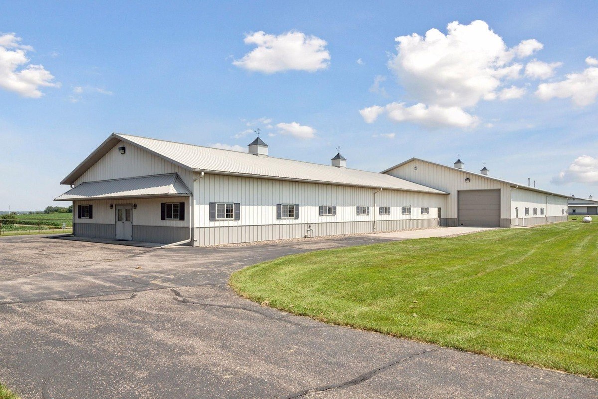 Spacious barn-style building with multiple sections and a paved driveway leading to it.