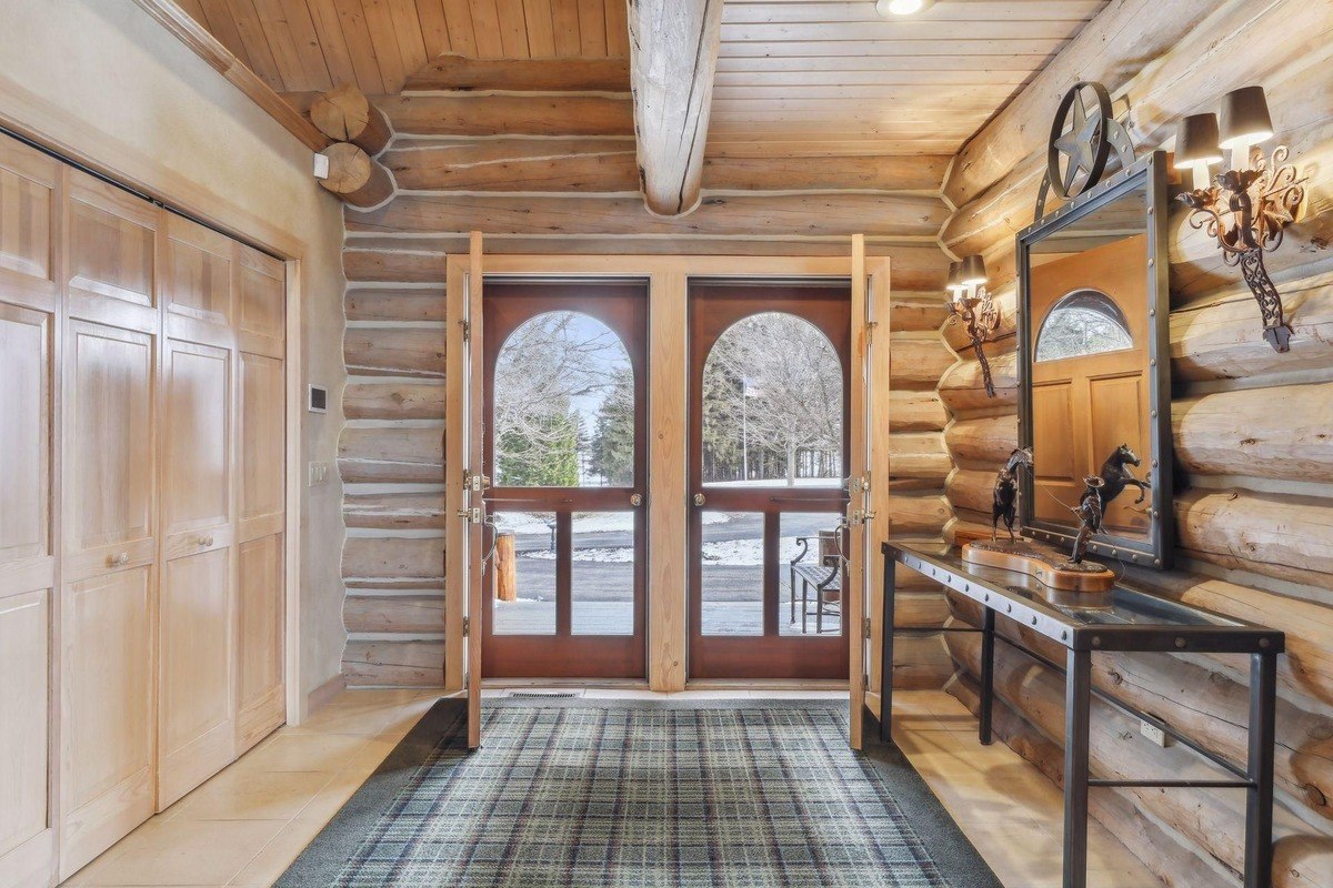 Entryway a log cabin-style foyer with double doors and a mirror-topped console table.