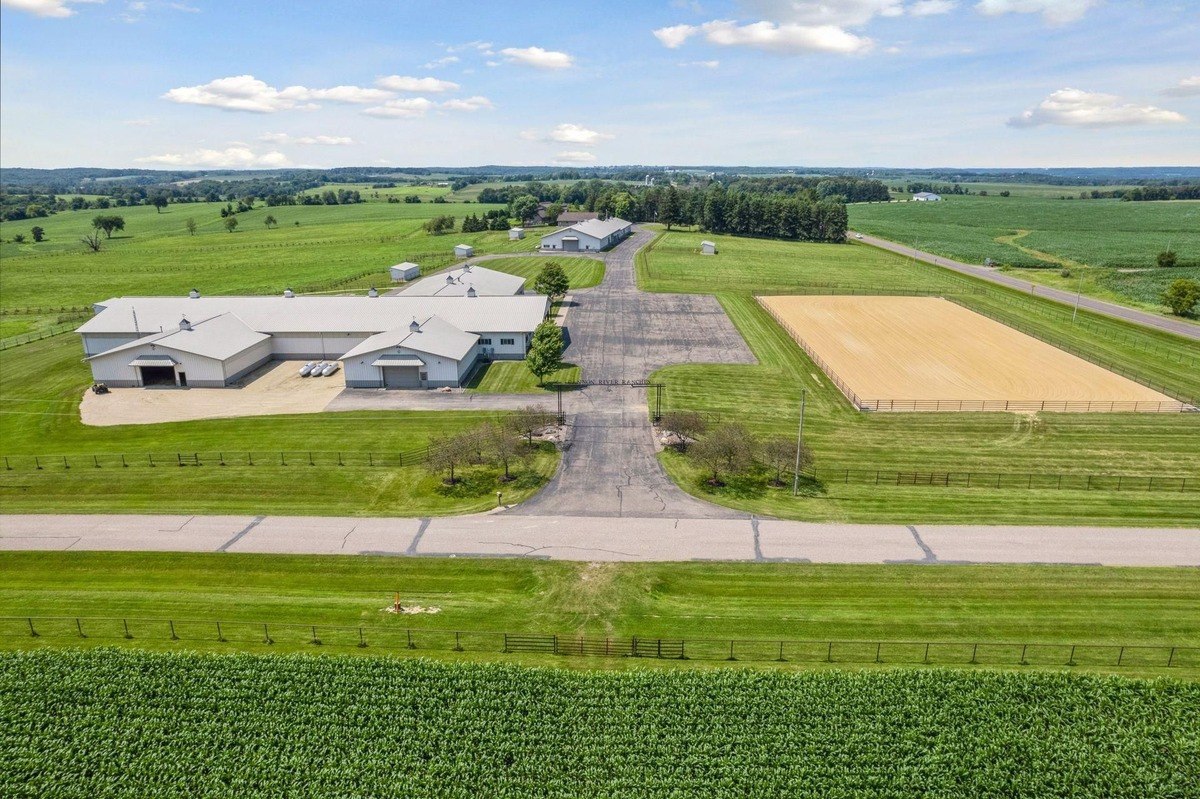 Bird's-eye view of ranch facilities, including buildings, arenas, and driveways.