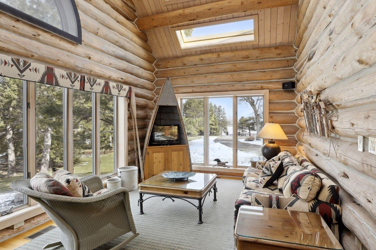 Sunroom cozy sitting area with large windows, natural light, and a decorative fireplace.