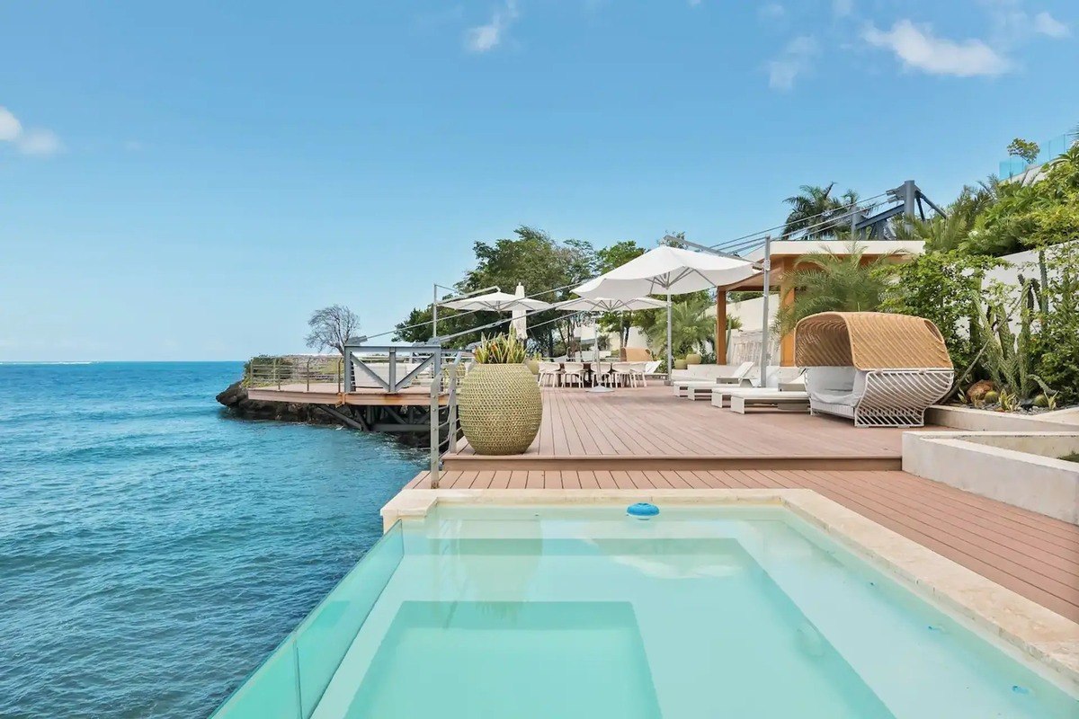 Oceanfront pool and deck area has lounge chairs and umbrellas.