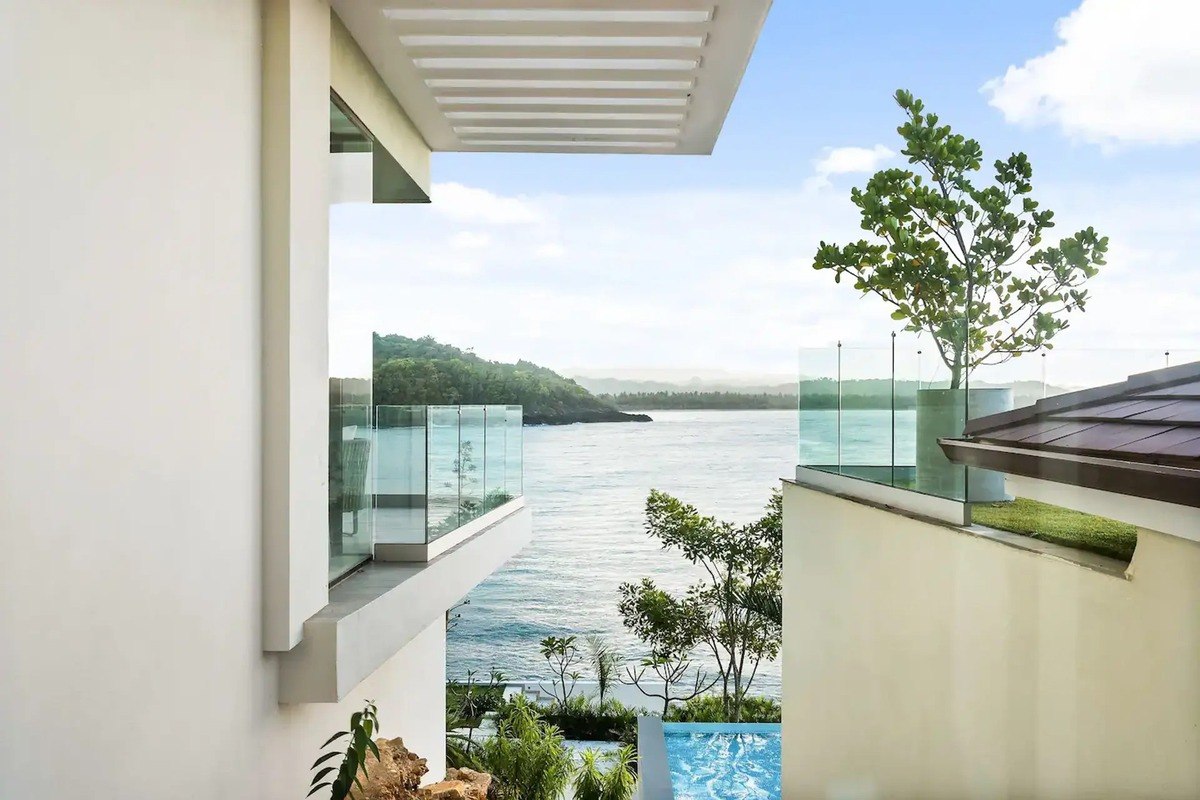 Ocean view is seen from between two modern buildings with glass railings.