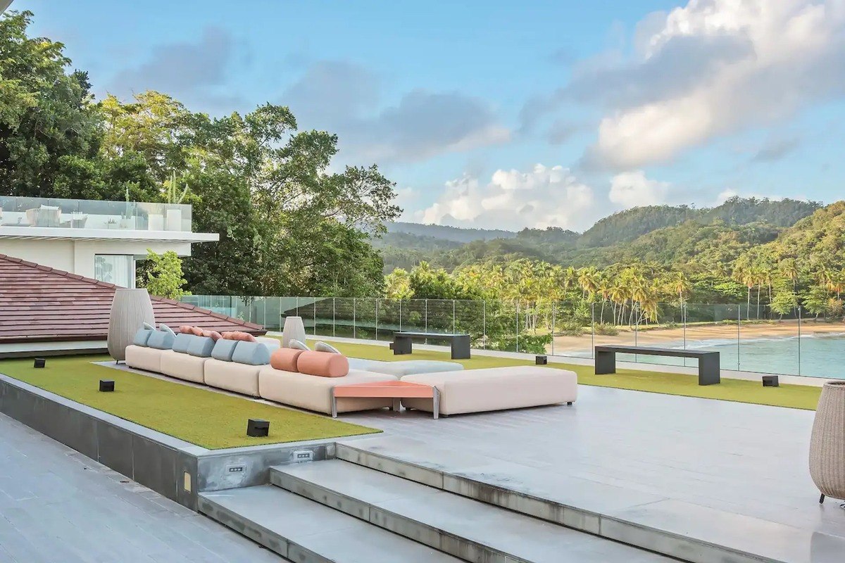 Outdoor patio has sectional sofa, steps leading down, and ocean view.