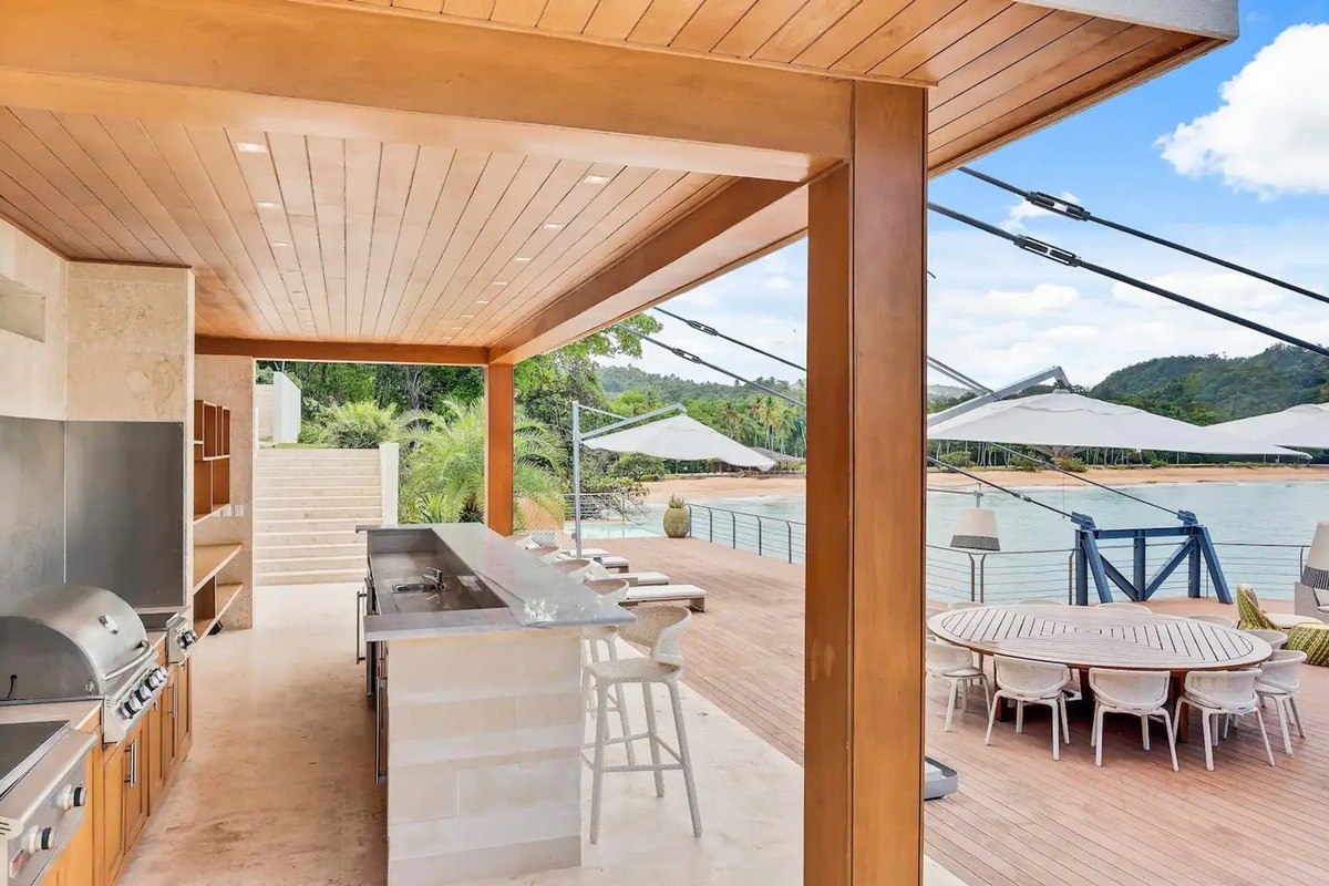 Outdoor kitchen has built-in grill, bar seating, and ocean view.