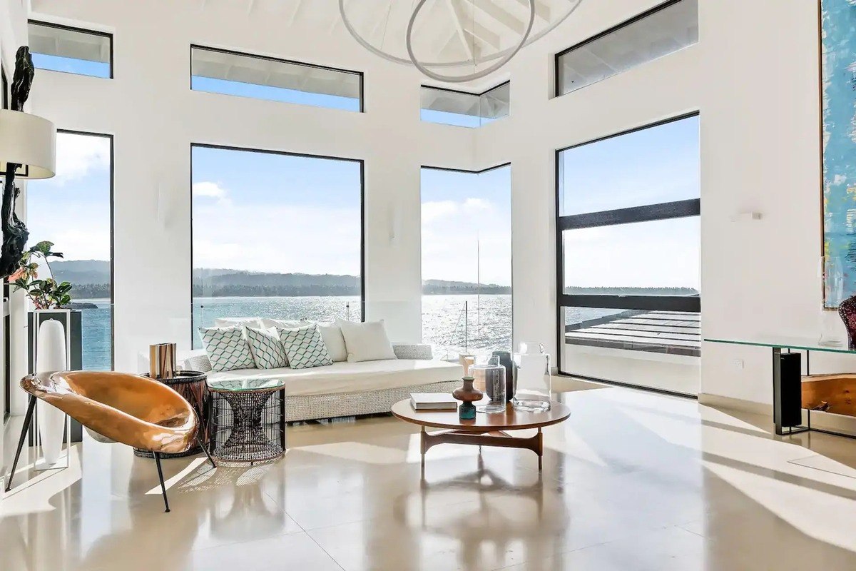 Living room has floor-to-ceiling windows offering panoramic water views.