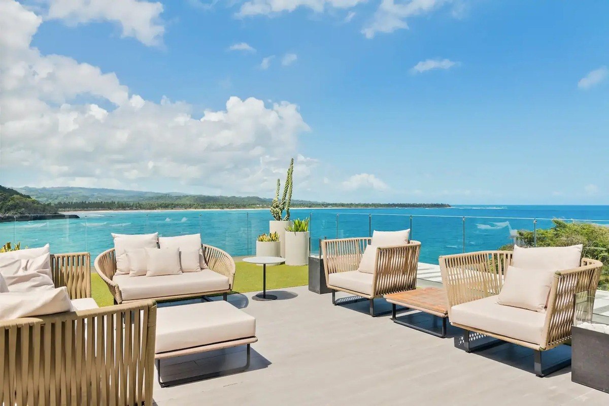 Oceanfront patio has wicker furniture and ocean view.